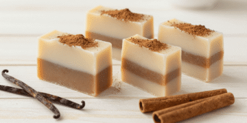 Sabonetes de canela e baunilha em camadas creme e marrom polvilhados com canela e paus de canela ao lado