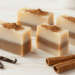 Sabonetes de canela e baunilha em camadas creme e marrom polvilhados com canela e paus de canela ao lado
