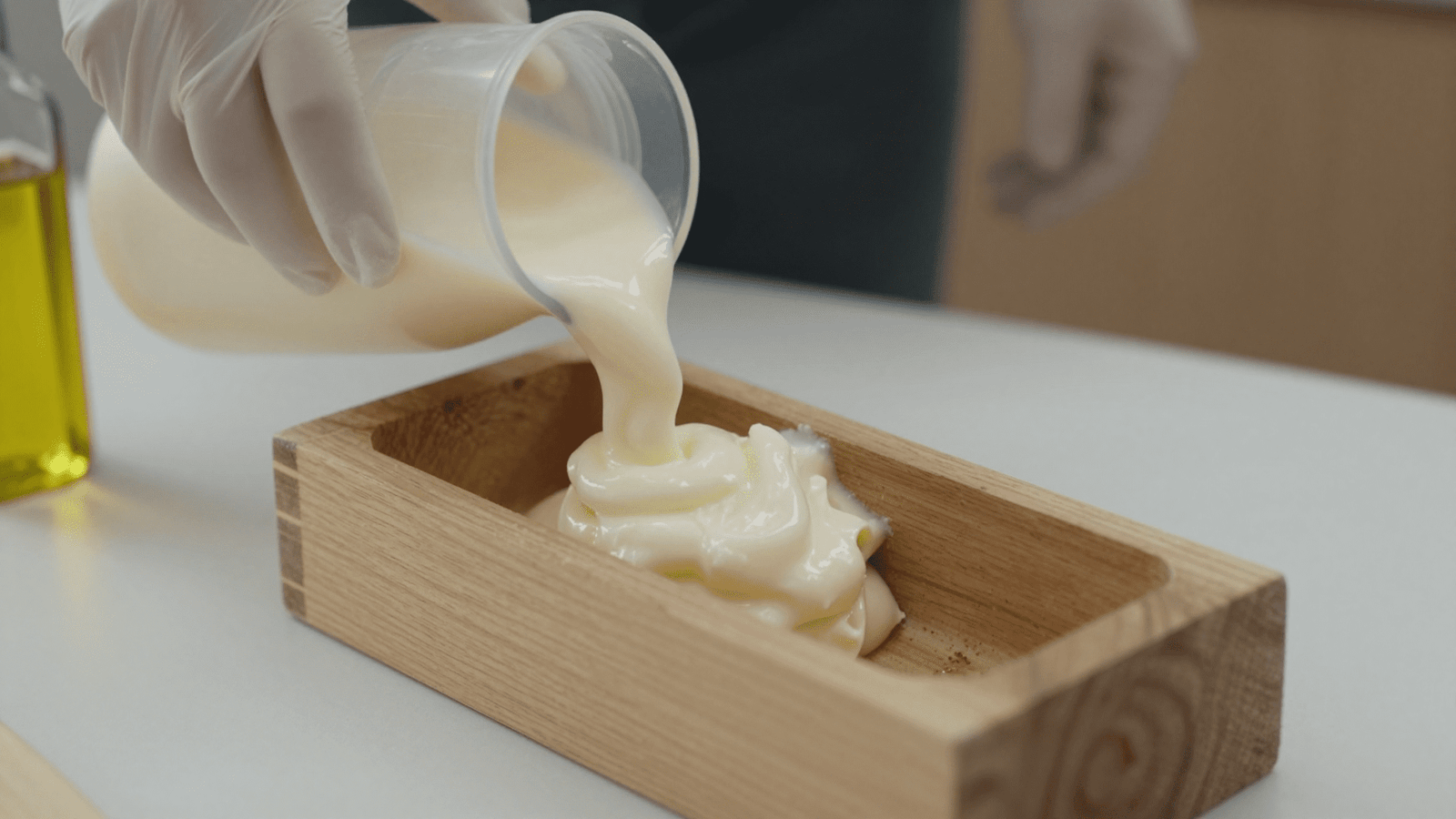 Preparo do sabão de castela no cold process: massa de sabão sendo despejada na forma com luvas de proteção