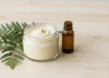 Condicionador natural de cipreste cremoso num pote com ramo de cipreste e oleo de argan ao lado