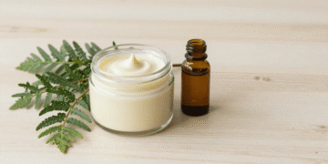 Condicionador natural de cipreste cremoso num pote com ramo de cipreste e oleo de argan ao lado