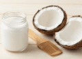 Pote de oleo de coco com cocos frescos e pente de madeira sobre mesa clara