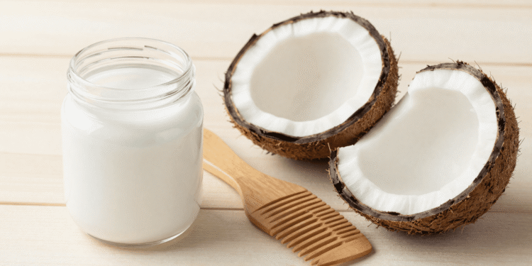 Pote de oleo de coco com cocos frescos e pente de madeira sobre mesa clara