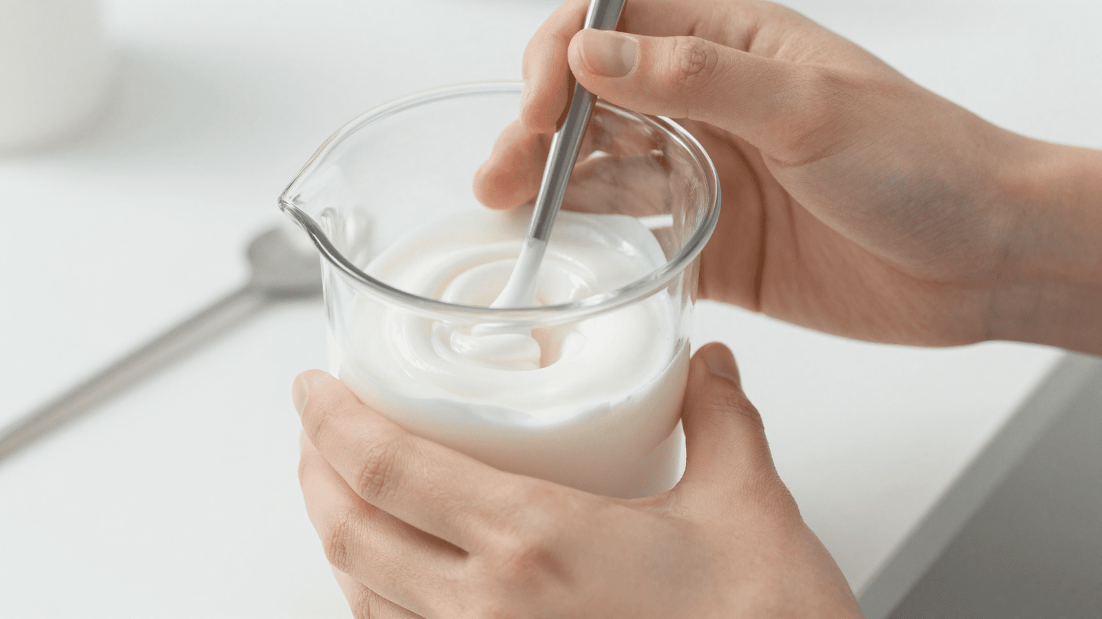 Preparo do creme Lanette: emulsão branca sendo mexida em béquer durante a formulação