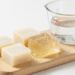 Cubos de base de glicerina transparente e branca sobre tabua de madeira