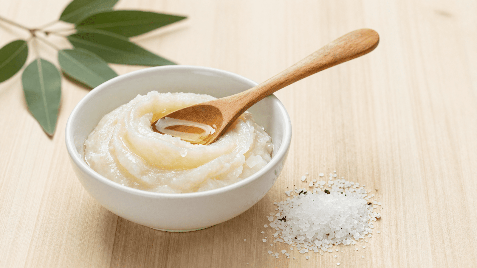 Esfoliante de sal grosso com tea tree pronto em pasta numa tigela com colher de madeira
