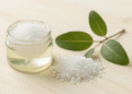Esfoliante de sal grosso com tea tree para os pes num pote com sal grosso e ramo de melaleuca ao lado