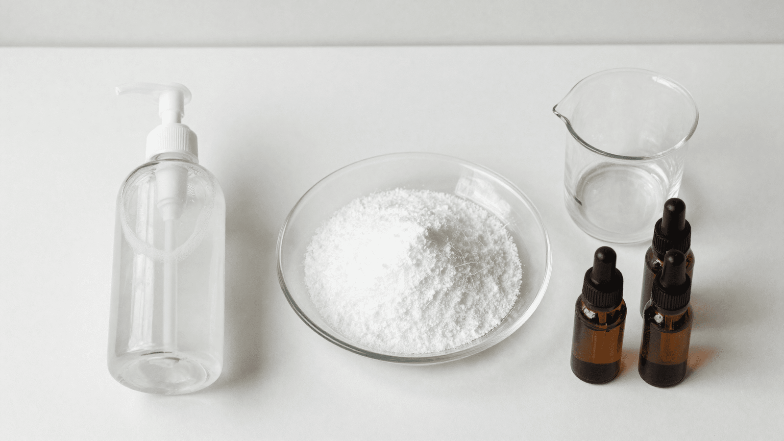 Ingredientes da espuma de limpeza natural: frasco espumador, SCI, bequer e oleos essenciais