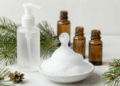 Frasco espumador liberando espuma de limpeza facial natural com ramo de pinho e oleos essenciais