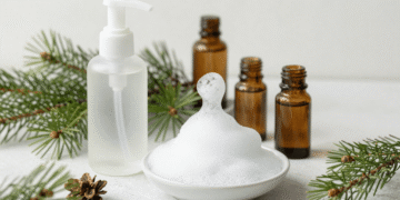 Frasco espumador liberando espuma de limpeza facial natural com ramo de pinho e oleos essenciais