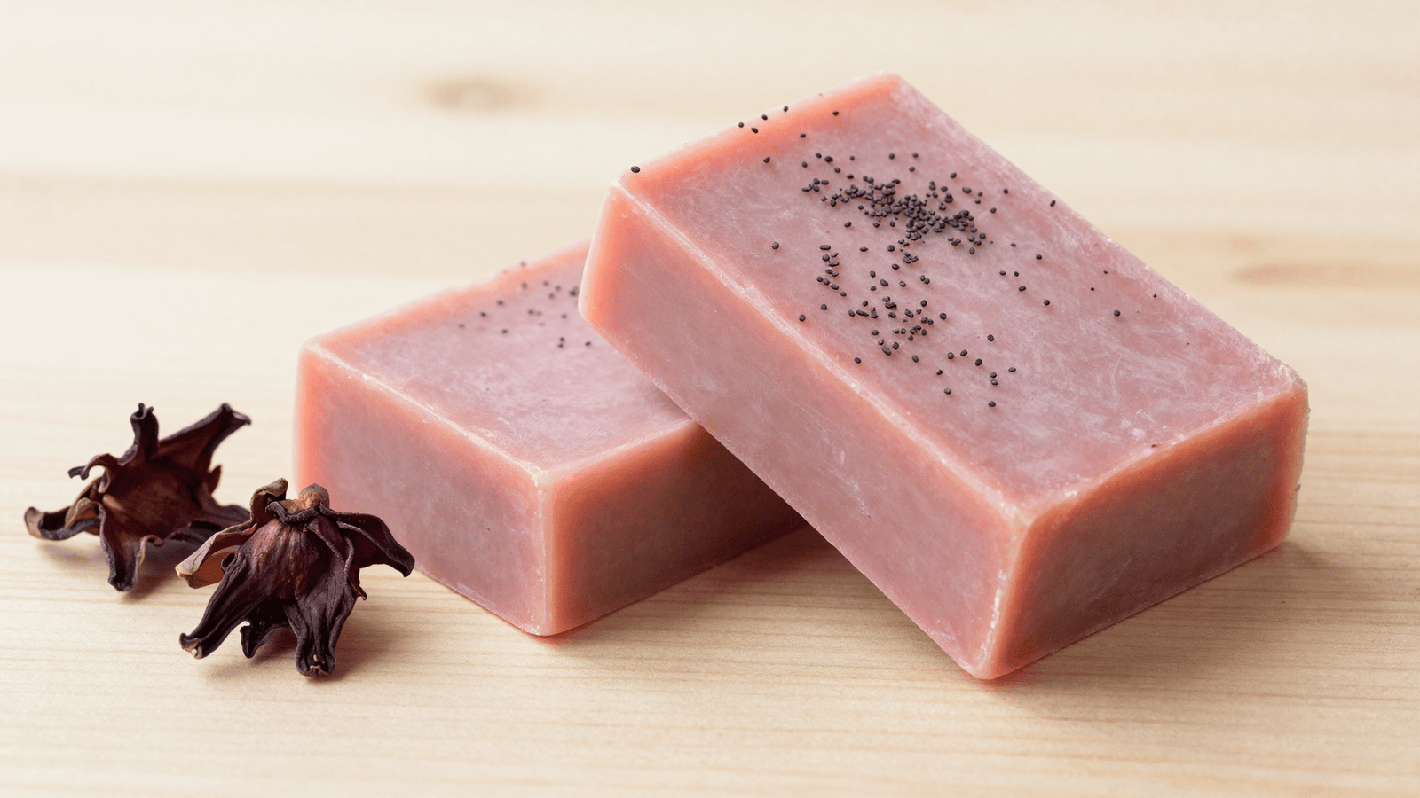 Sabonetes de hibisco rosados com sementes de papoula e flor de hibisco ao lado