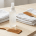 Leave-in caseiro num frasco spray com toalha e pente de madeira ao lado sobre mesa clara