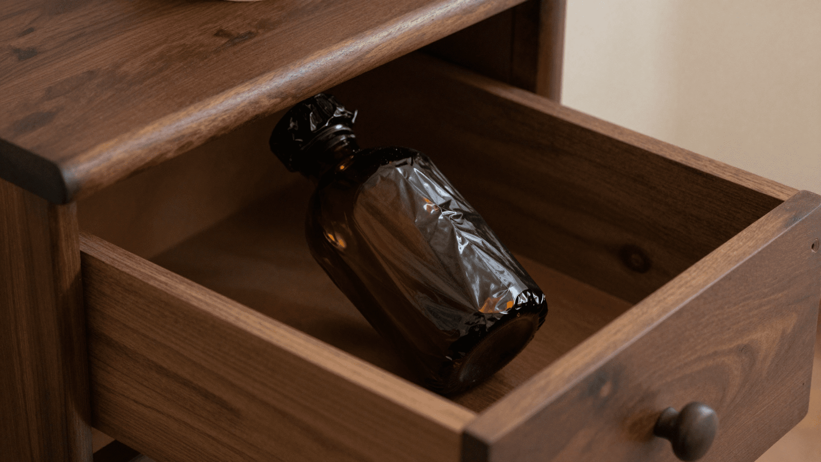 Frasco de aromatizador envolto em plastico preto guardado no armario escuro para macerar