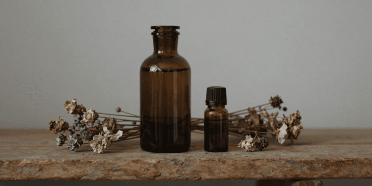 Frasco ambar de perfume artesanal em maceracao com flores secas e oleos essenciais