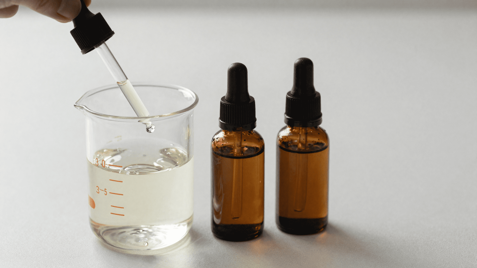 Misturando agua, glicerina e gotas de oleo essencial num bequer para o spray bloqueador de odor