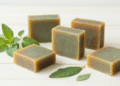 Sabonetes naturais de oregano e neem esverdeados com ramos de oregano e folhas de neem ao lado