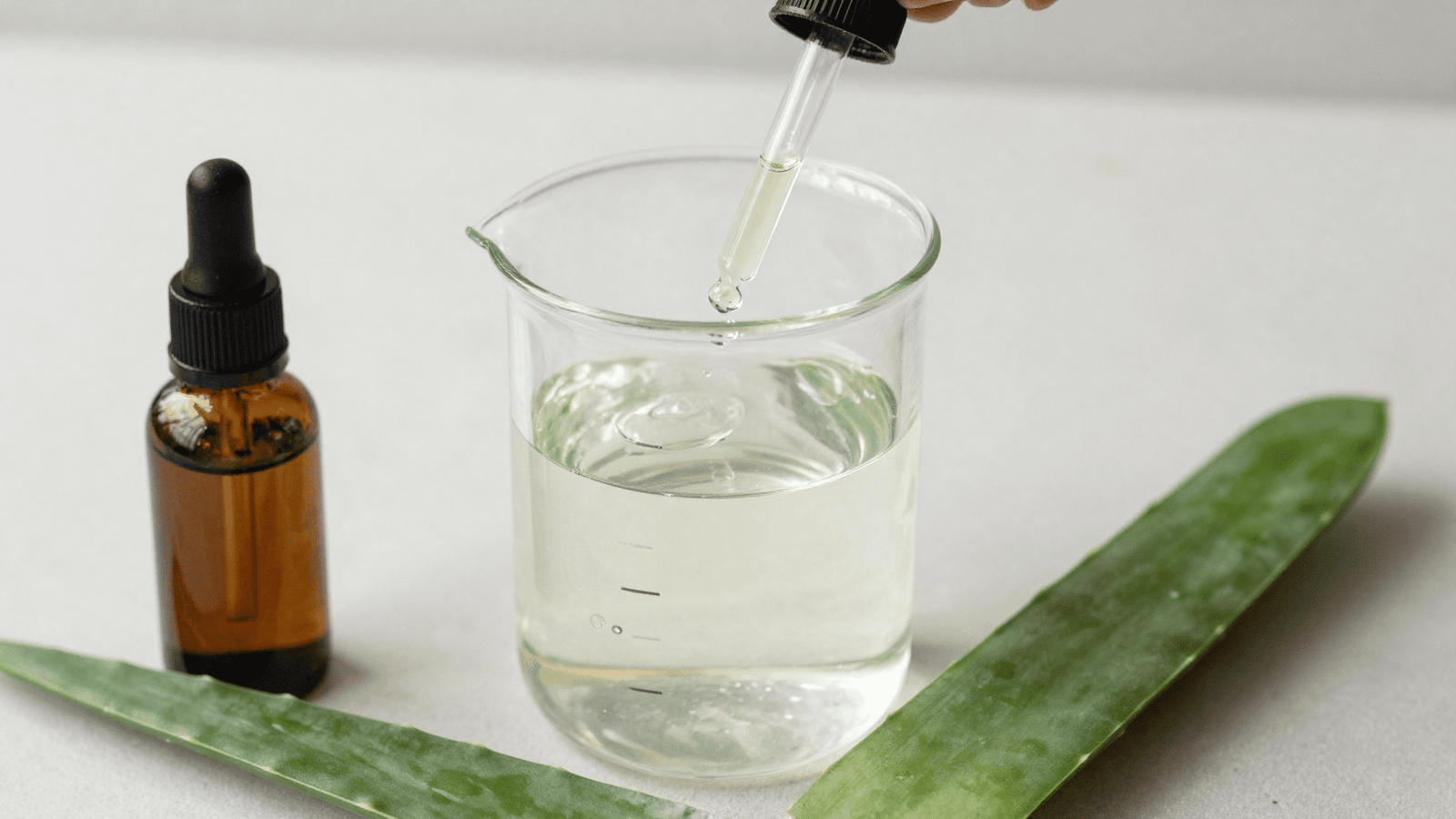 Misturando soro fisiologico, aloe vera e gotas de oleo essencial num bequer para o spray pos-sol