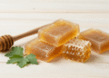 Sabonetes de propolis e confrei cor de mel com favo de mel e folhas de confrei ao lado