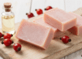 Sabonetes artesanais de rosa mosqueta rosados sobre tabua de madeira com frutos e oleo