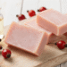 Sabonetes artesanais de rosa mosqueta rosados sobre tabua de madeira com frutos e oleo
