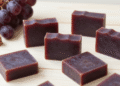 Sabonetes artesanais de vinho cor de vinho tinto com uvas roxas e rolha ao lado