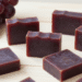 Sabonetes artesanais de vinho cor de vinho tinto com uvas roxas e rolha ao lado