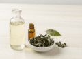 Tonico facial natural num frasco de vidro com folhas de cha verde e oleo essencial ao lado