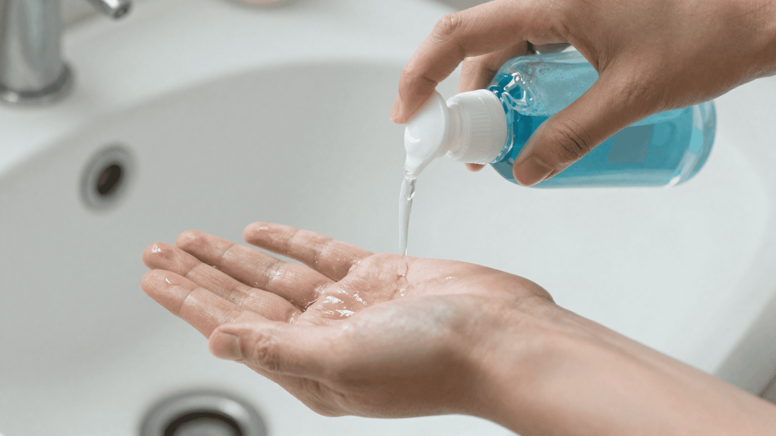Álcool gel transparente sendo aplicado nas mãos limpas sobre uma pia clara