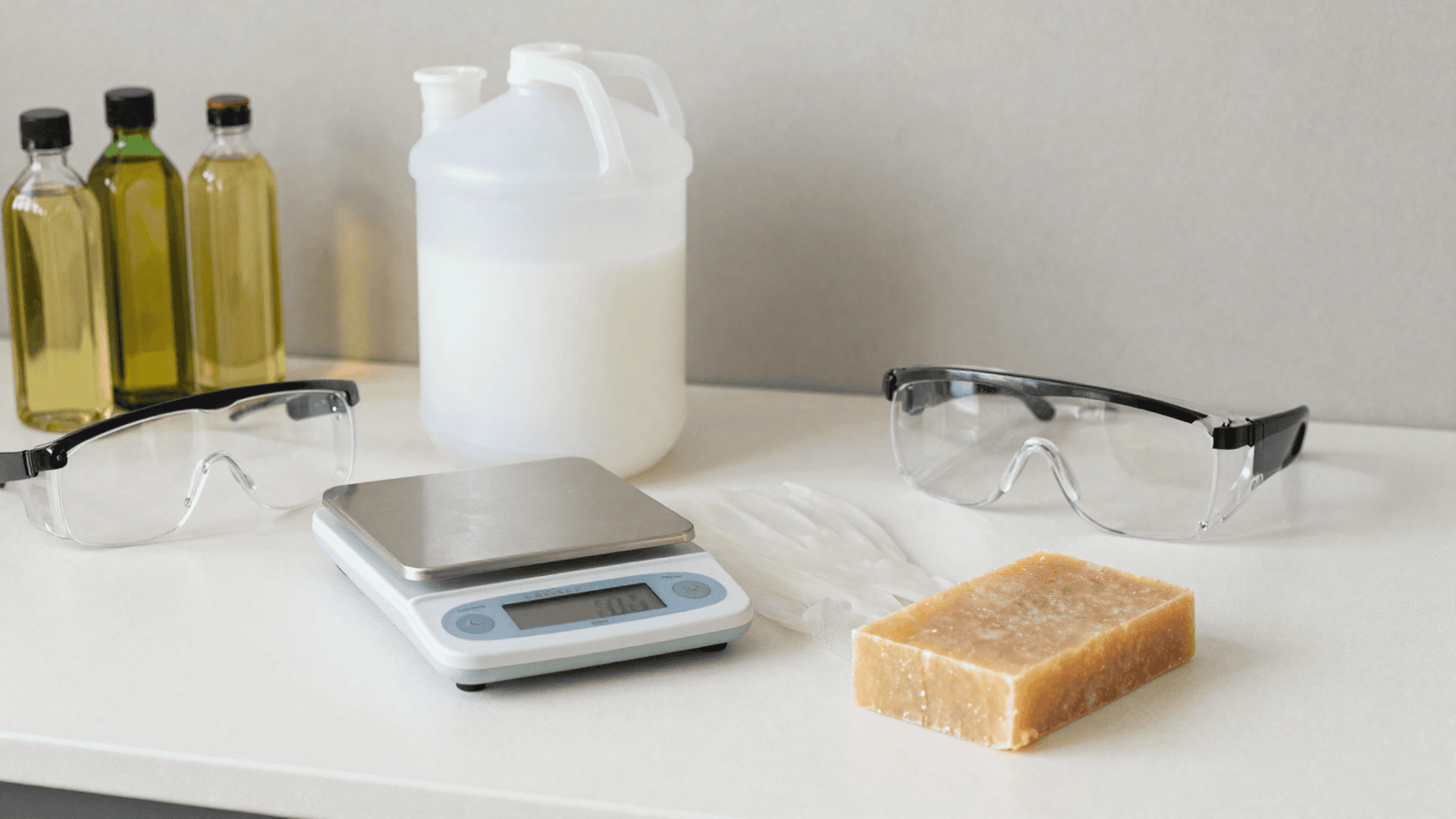 Balança digital, óculos e luvas de segurança e óleos, montagem de estudo de cold process