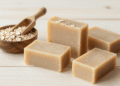 Sabonetes de aveia artesanais com flocos de aveia, tigela de aveia crua e colher de madeira ao lado