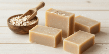 Sabonetes de aveia artesanais com flocos de aveia, tigela de aveia crua e colher de madeira ao lado