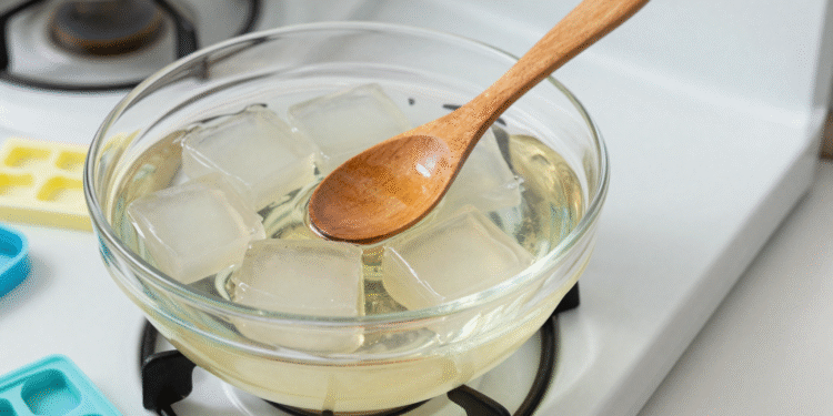 Cubos de base glicerinada derretendo em banho-maria com colher de madeira e formas de sabonete ao lado