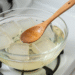 Cubos de base glicerinada derretendo em banho-maria com colher de madeira e formas de sabonete ao lado