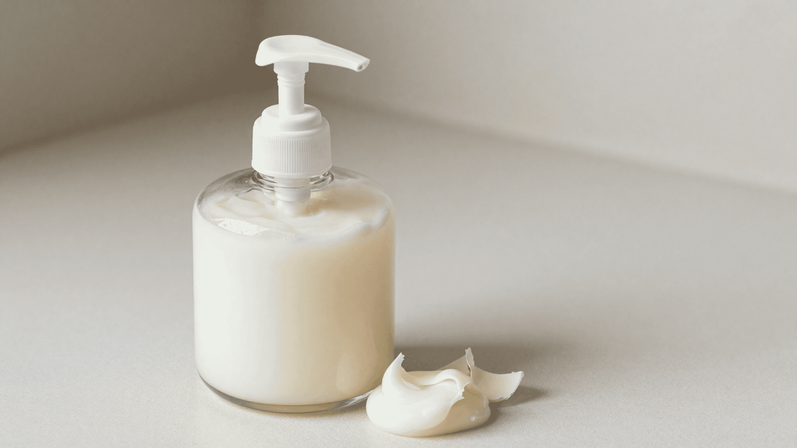 Sabonete líquido branco e cremoso em um dispenser de vidro com bico pump