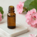 Frasco âmbar de óleo essencial de gerânio cercado de flores de gerânio rosa e folhas verdes