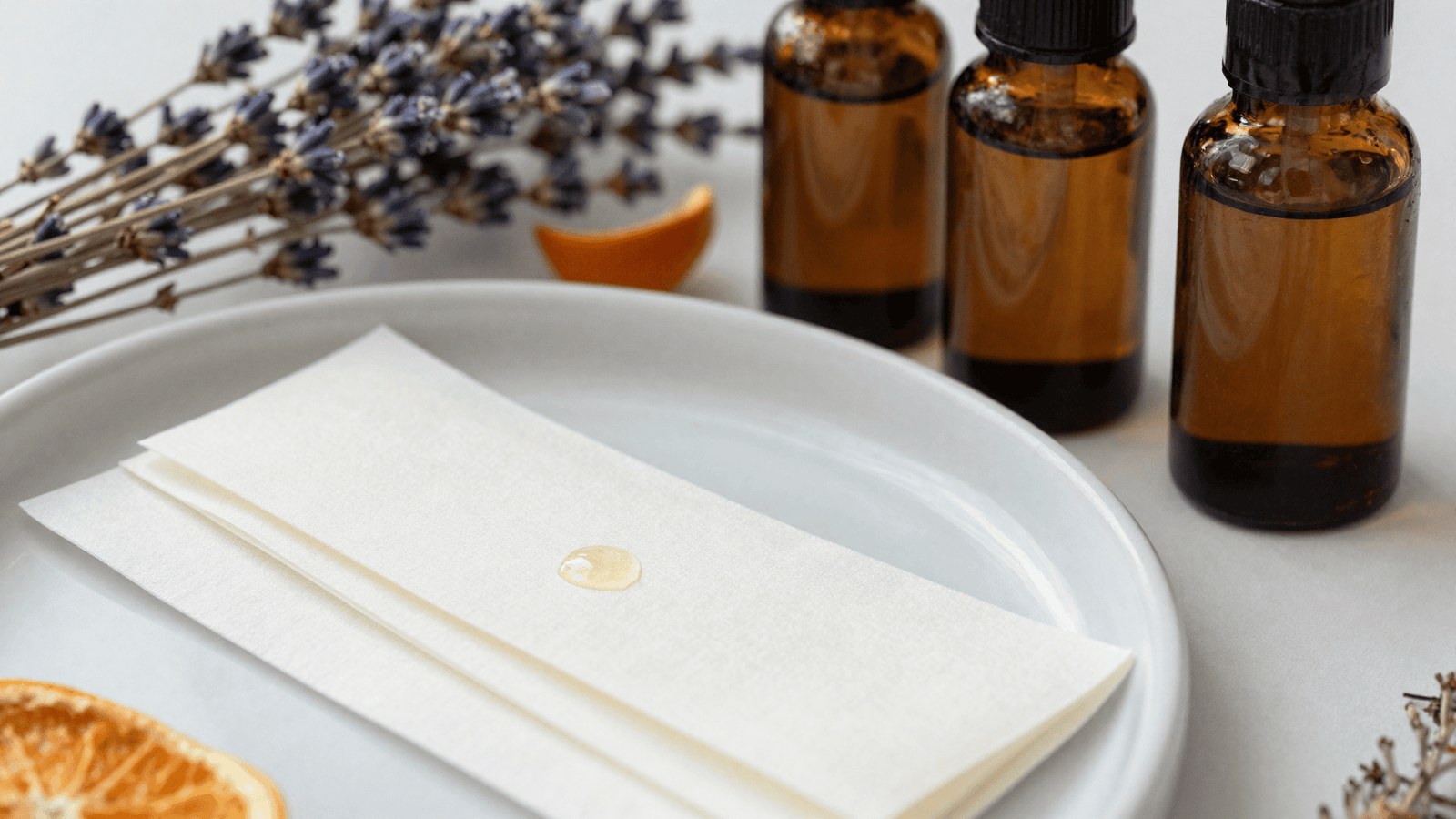 Fitas de papel para teste de aroma com gotas de essência ao lado de frascos âmbar abertos